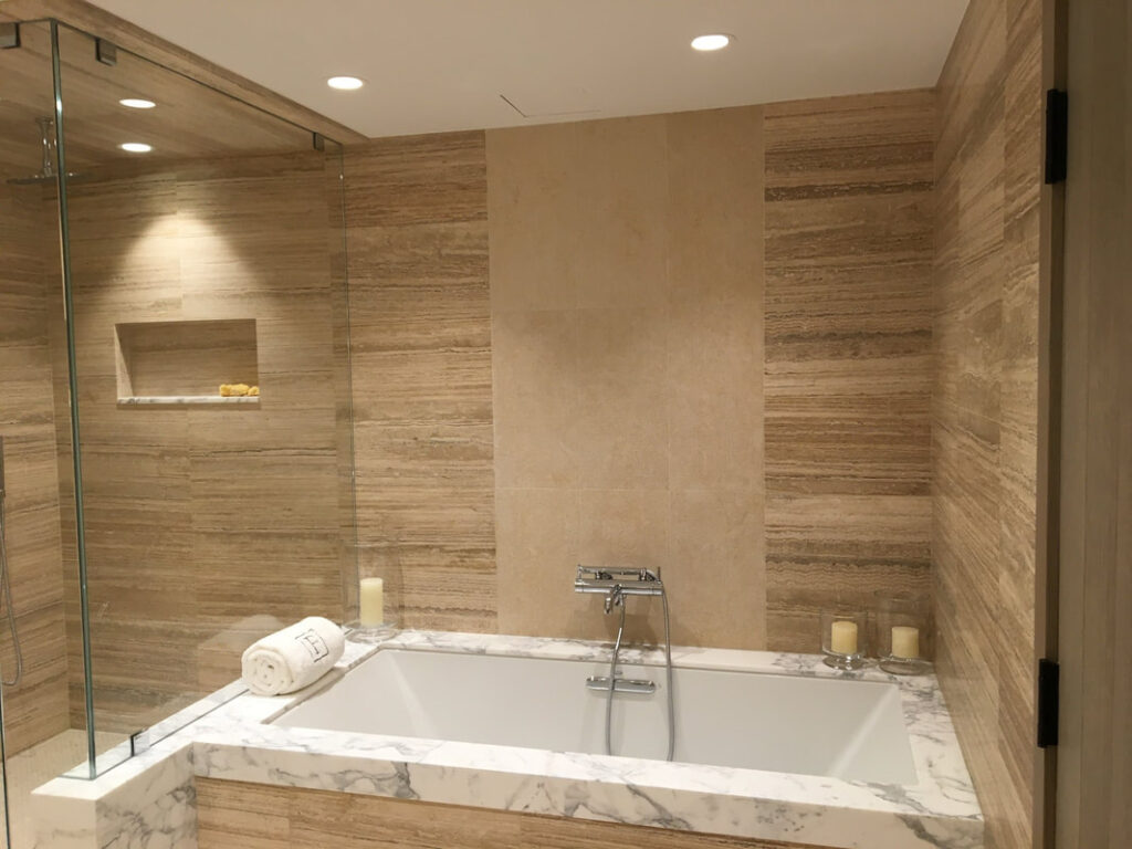 A bathroom with a large tub and tiled walls.