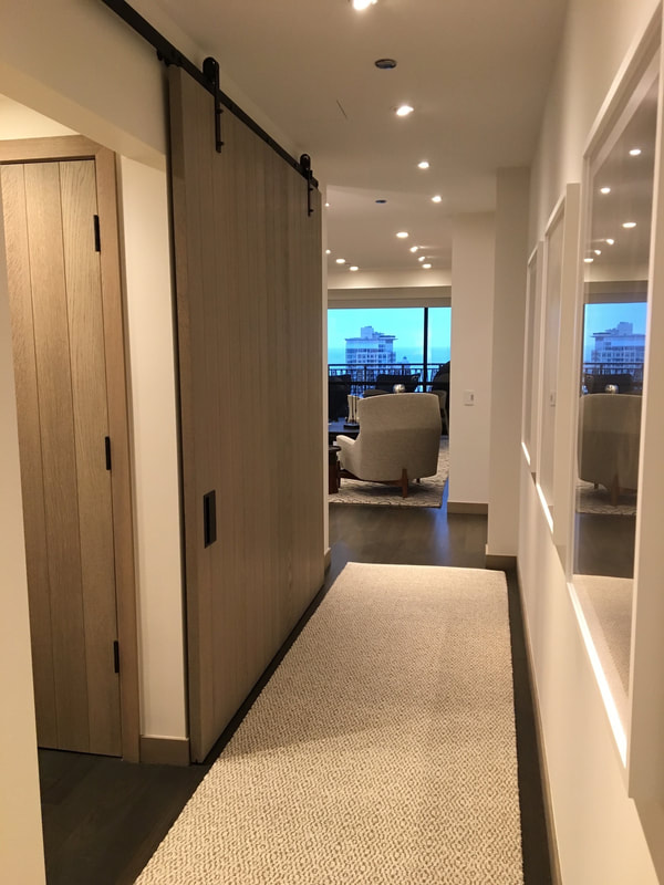A hallway with sliding doors and a rug.