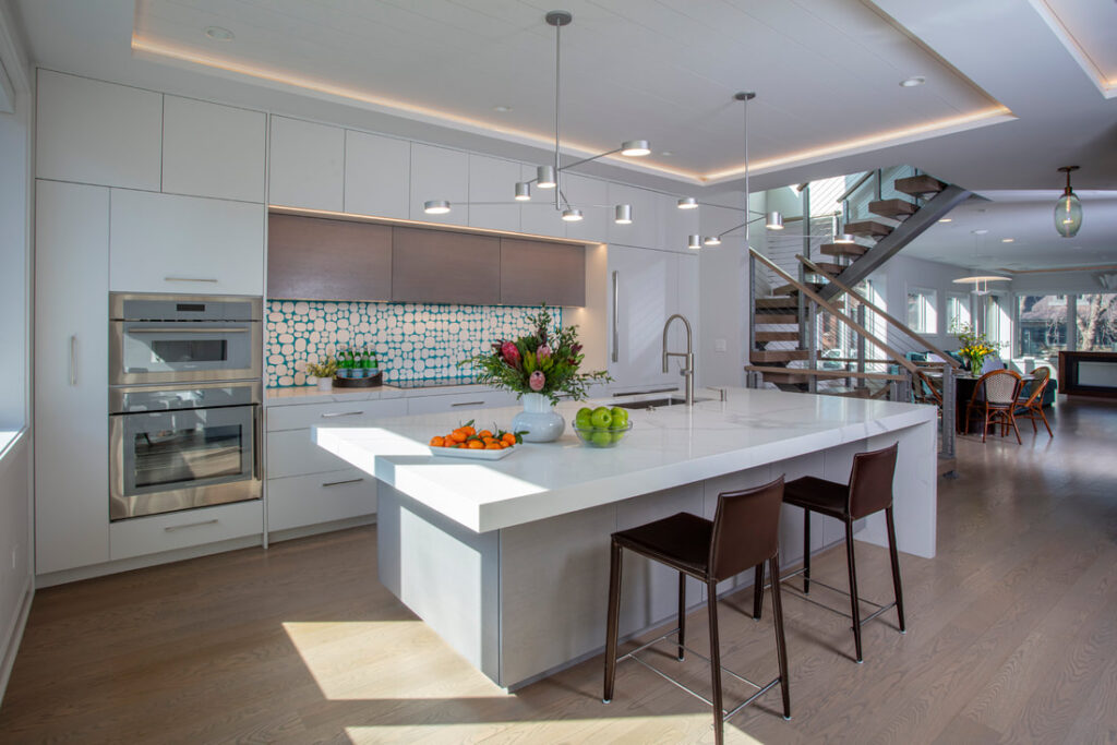 A kitchen with white cabinets and brown chairs