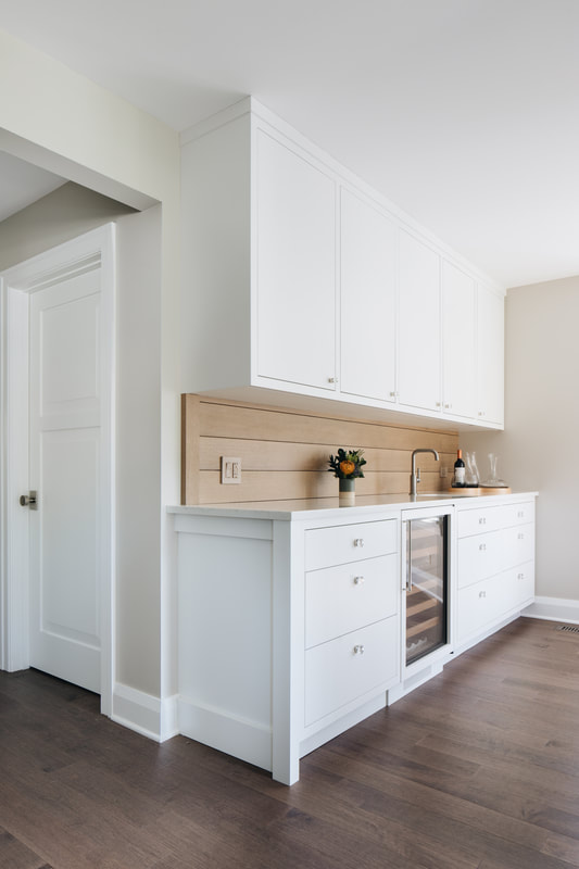 A kitchen with white cabinets and wood paneling.