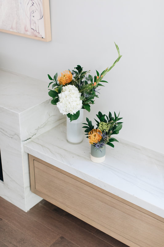 Two vases with flowers on a counter top.