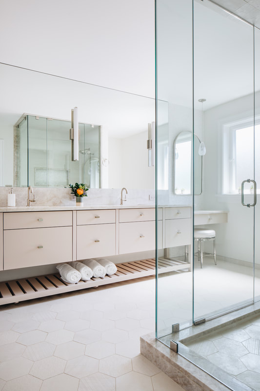 A bathroom with a glass shower door and white cabinets.